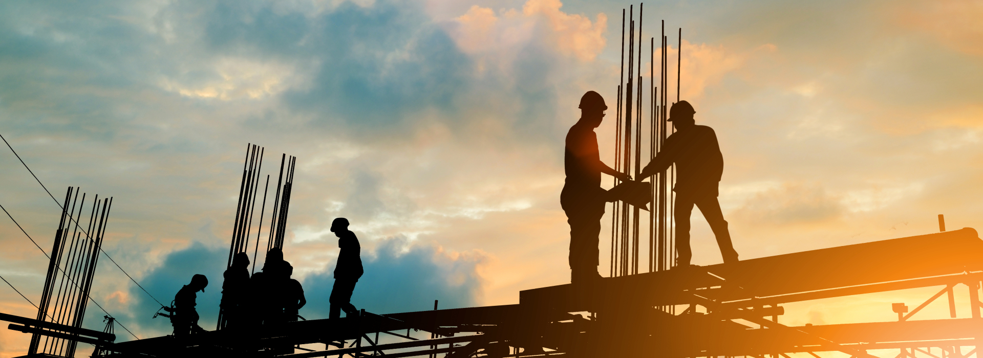 construction workers building a highway with the sun setting in the background